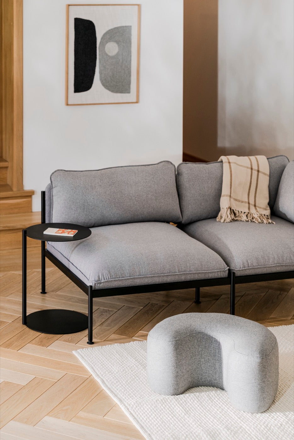 black indoor living-room sofas light-grey poufs side-tables 